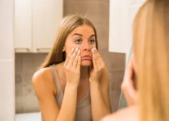 девушка с Ozempic face рассматривает себя в зеркало